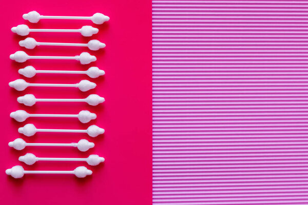top view of cosmetic cotton swabs on bicolor pink and purple background