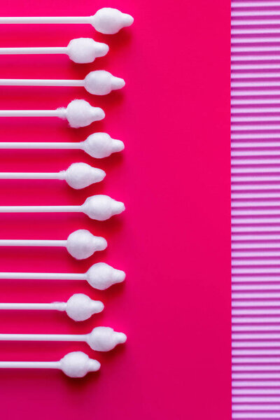 top view of ear sticks on pink and violet textured background