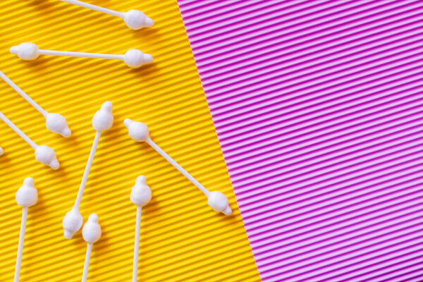 top view of hygienic ear sticks on yellow and violet textured background