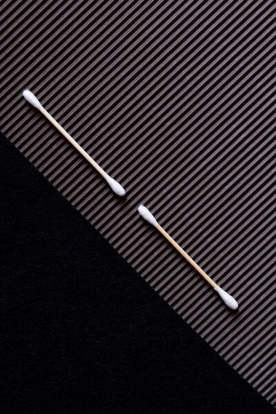 top view of two cotton swabs on textured and black background