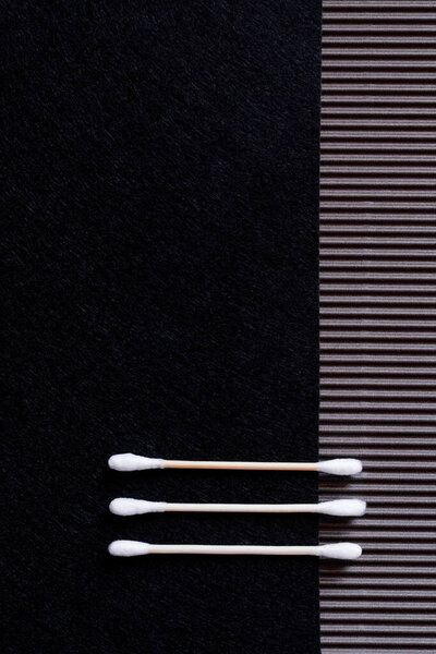 top view of two cotton ear sticks on black and textured background with copy space