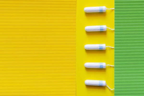 vertical row of tampons on yellow and green textured background
