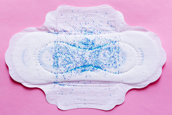 top view of white panty liner with sequins on violet background