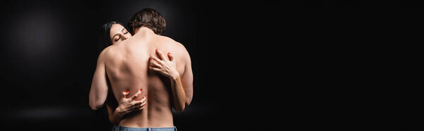 Passionate woman scratching back of muscular man on black background, banner 