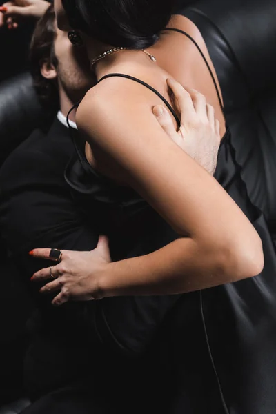 情熱的な女性でスーツ接吻セクシー女性でサテンドレス上のカウチ隔離された黒 — ストック写真