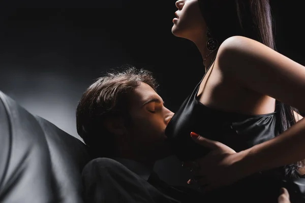 Young Man Kissing Breast Passionate Girlfriend Leather Couch Black Background — ストック写真