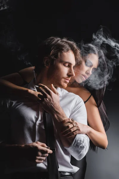 Morena Mulher Tocando Namorado Desgaste Formal Com Cigarro Fundo Preto — Fotografia de Stock