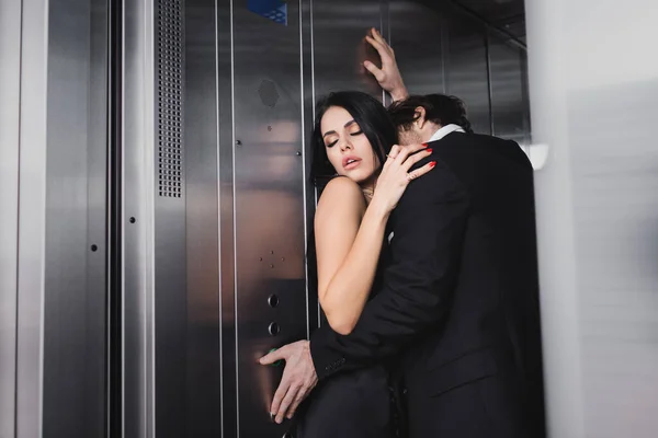 Man Kissing Sensual Girlfriend Pressing Button Elevator — стоковое фото