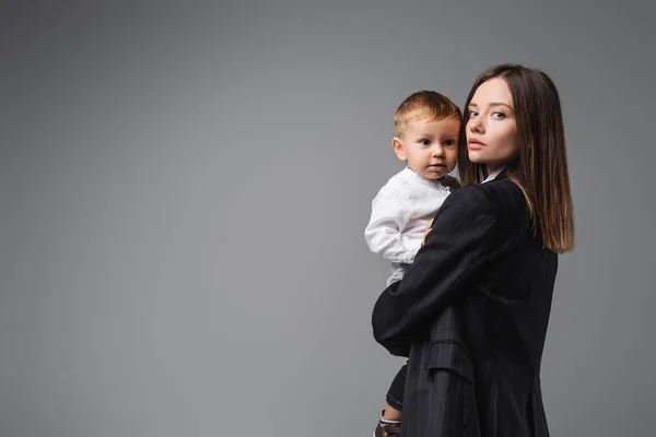 Woman Black Blazer Holding Toddler Son Looking Camera Grey — 스톡 사진