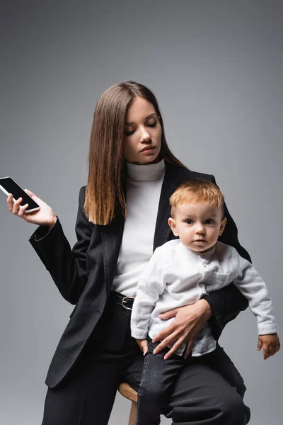 Woman Holding Smartphone Blank Screen Toddler Son Isolated Grey — Stock Fotó