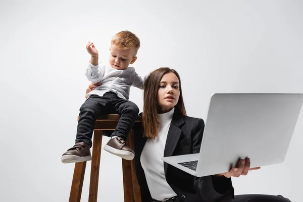 Businesswoman Looking Laptop Son Sitting High Stool Isolated Grey — Foto de Stock