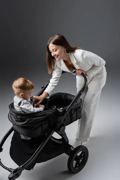 Feliz Mujer Tocando Niño Hijo Sentado Negro Cochecito Gris — Foto de Stock