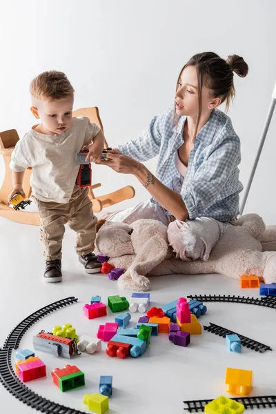 Young Woman Holding Toy Train While Playing Toddler Son White — Foto de Stock