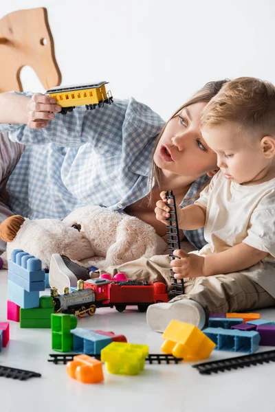 Giovane Madre Holding Giocattolo Treno Vicino Giocare Figlio Bianco — Foto Stock