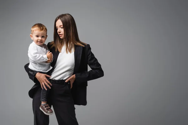 Businesswoman Standing Hand Hip While Holding Smiling Son Isolated Grey — 스톡 사진