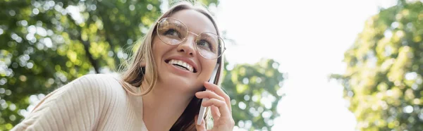 Nízký Úhel Pohledu Šťastné Ženy Brýlích Mluví Smartphone Banner — Stock fotografie