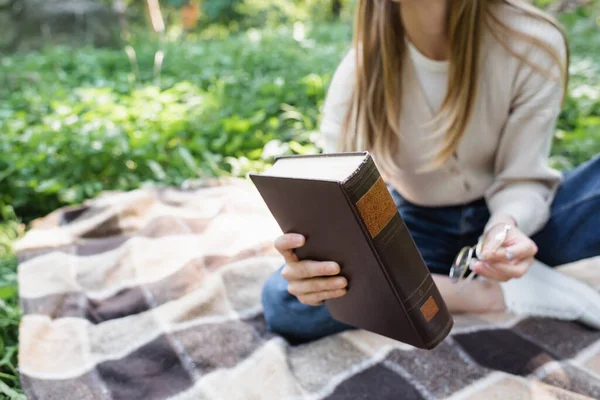 Beskärd Över Kvinnan Håller Bok Och Glasögon Medan Sitter Rutig — Stockfoto