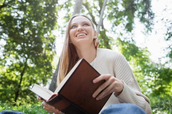 Vista Ángulo Bajo Mujer Feliz Sosteniendo Libro Sonriendo Parque — Foto de Stock