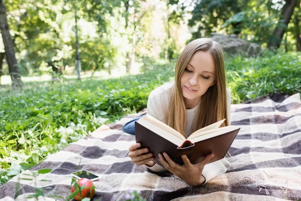 Donna Che Legge Libro Mentre Giace Vicino Smartphone Mela Sulla — Foto Stock