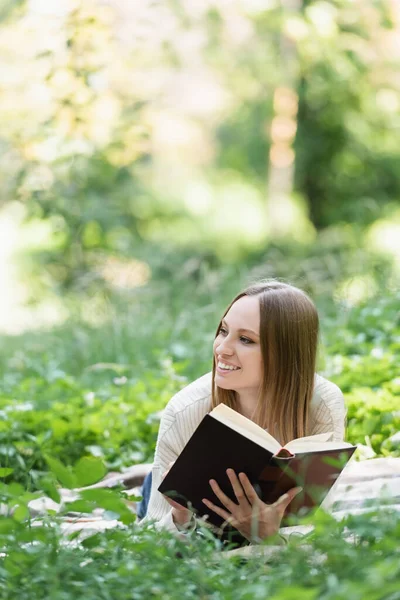 Весела Жінка Читає Книгу Лежачи Ковдрі Навколо Зеленої Трави — стокове фото