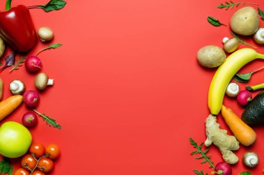 Flat lay with whole vegetables and fruits on red background with copy space 