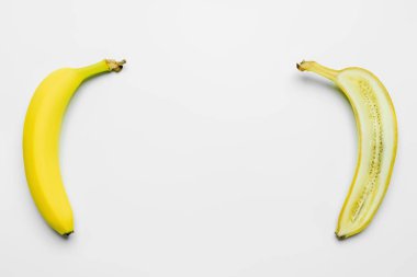 Top view of organic whole and cut bananas on white background