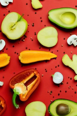 Top view of cut fresh food and peppercorns on red background