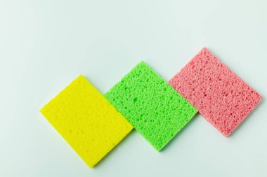 top view of yellow, green and pink sponge rugs on grey background