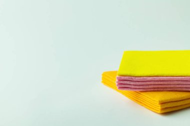 orange, yellow and pink cleansing rags on grey background with copy space clipart