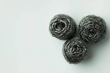 top view of three stainless wire scourers on grey background clipart