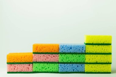 stack of porous multicolored sponge scourers on grey background