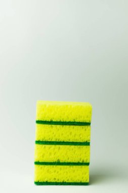 stack of porous yellow and green sponge scourers on grey background clipart