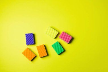top view of colorful sponges on bright yellow background with copy space