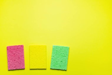 top view of multicolored absorbent sponge rugs on yellow background with copy space