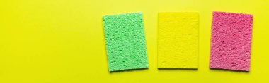 top view of bright absorbent sponge rugs on yellow background, banner