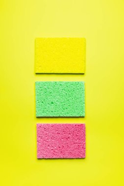 top view of bright multicolored sponge cloths on yellow background