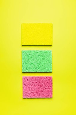 top view of bright multicolored sponge cloths on yellow background clipart