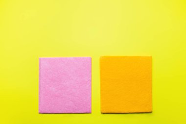 top view of bright pink and orange dishrags on yellow background