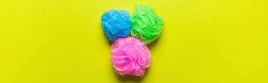 top view of bright multicolored mesh washcloths on yellow background, banner