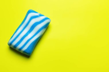top view of striped white and blue soap bar on bright yellow background