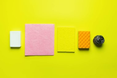 top view of soap near dishrags, sponge scourer and steel scrubber on yellow background clipart