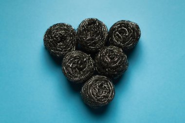 top view of triangle made of steel scourers on blue background