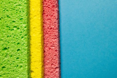top view of absorbent multicolored sponge rugs on blue background