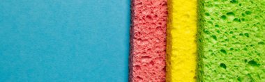 close up view of green, yellow and pink sponge rags on blue background, banner