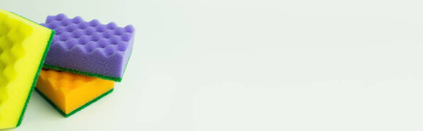 yellow, purple and orange sponges on grey background with copy space, banner