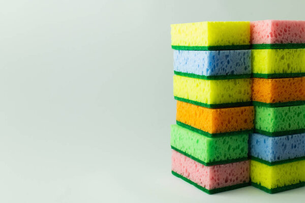 stacks of multicolored sponges on grey background with copy space