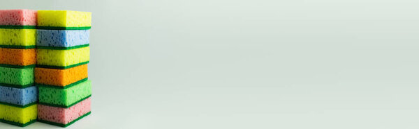 bright multicolored scouring pads stacked on grey background with copy space, banner