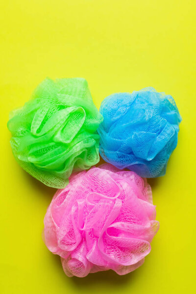 top view of colorful exfoliating body puffs on yellow background