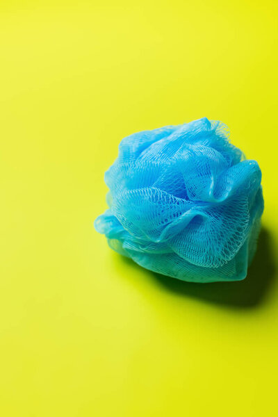 top view of blue mesh washcloth on bright yellow background