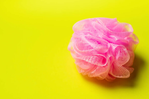 top view of pink mesh washcloth on bright yellow background